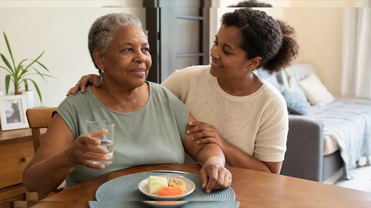 Older adult sitting with caregiver support to drink water more safely
